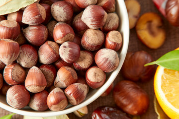 Various raw nuts: hazelnuts, pistachios, chestnuts, dates and oranges.