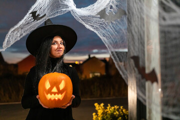 Woman witch carrying a pumpkin for Halloween night - Spooky scene with halloween symbols and signs ...
