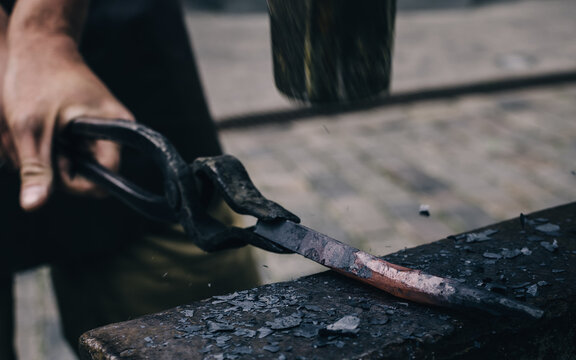 A blacksmith working with simple object by forging the metal. Flame texture close-up. Art, traditional craft, handicraft, history, industry, smithing process, wrought iron and steel details - Powered by Adobe