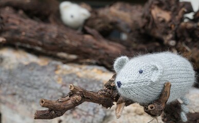 A gray knitted mouse placed on a tree branch as a decoration. 