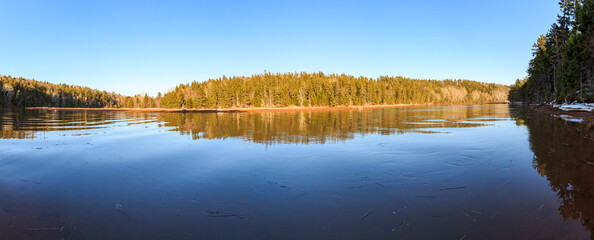 Calming panoramic reflection of clear skies and a forested hill in Strathgartney Provincial Park, Prince Edward Island, Canada