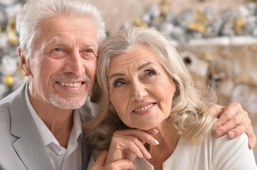 Hugging senior couple with blurred Christmas decorations