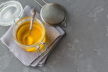 Healthy homemade Ghee or clarified butter in a jar on grey concrete background. Healthy Ayurveda...