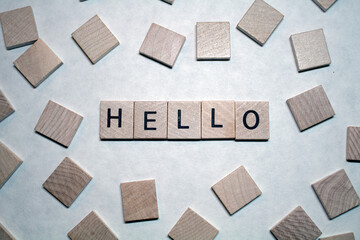HELLO written on square wooden blocks. Wooden tiles with black letters on a white background, surrounded by blank game pieces