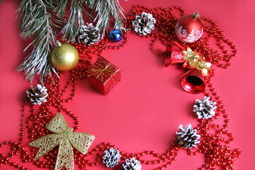 Fototapeta na wymiar Christmas background in red with Christmas toys, cones in the snow and Christmas bells