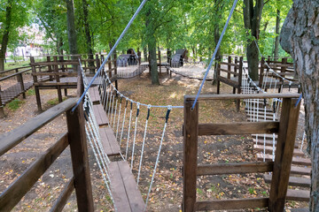 rope Park for children in the park. The bridge of logs tied to the ropes. Autumn park. painted wooden boards