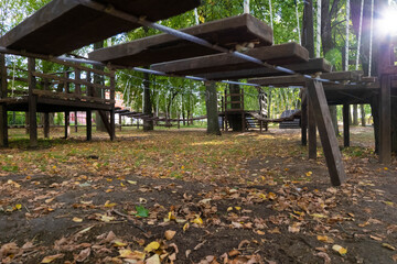 The bridge of logs tied to the ropes. lonely Broken bridge. Without children. Autumn park. Painted wooden plank. rope Park for kids in the green forest.