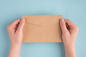 Fototapeta premium First person people above top overhead close up view photo of female woman hands holding one envelope in hands isolated over pastel color blue background
