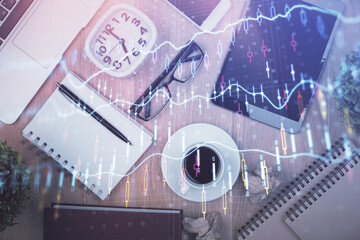 Double exposure of financial chart hologram over desktop with phone. Top view. Mobile trade platform concept.
