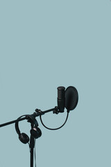 Items for podcasting: professional microphone and earphones isolated on blue background. Place for...