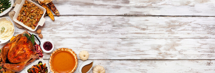 Traditional Thanksgiving turkey dinner. Top view corner border on a rustic white wood banner background with copy space. Turkey, mashed potatoes, stuffing, pumpkin pie and sides.