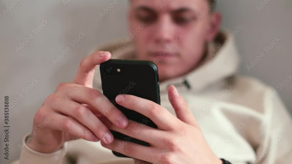 Poster using the phone in the hands of a guy sitting on the couch. checking notifications on your smartphon