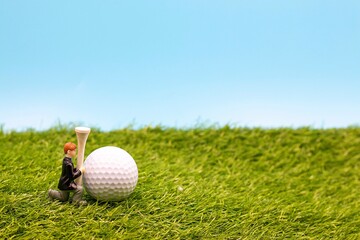 Golf wedding with golf ball and tee are on green grass with blue sky background