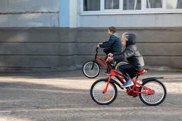 Fototapeta na wymiar Two boys ride bicycles on paved road. Children ride on Bicycle who is faster