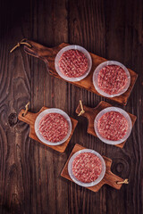 Raw hamburgers on cutting board with wood pile background - Top view