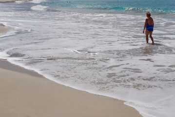 Single older woman walking along the beach