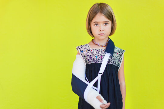trauriges Kind mit einem Gips vor gelber Wand