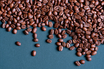 Roasted and aromatic Coffee beans on  blue colored surface as background. Top view with and copy space for text. Macro photo of fresh arabica coffee beens. Selective focus.