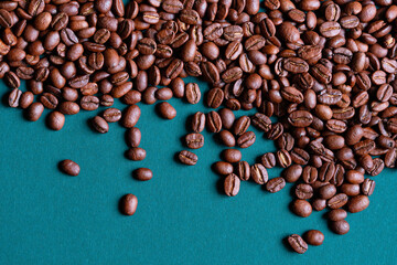 Roasted and aromatic Coffee beans on menthe blue colored  surface as background. Top view with and copy space for text. Macro photo of fresh arabica coffee beens.