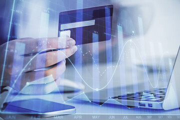 Multi exposure of woman on-line shopping holding a credit card and financial graph drawing. Stock market E-commerce concept.