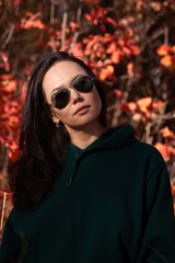 portrait of a beautiful asian young woman in sunglasses in the autumn forest at sunset.