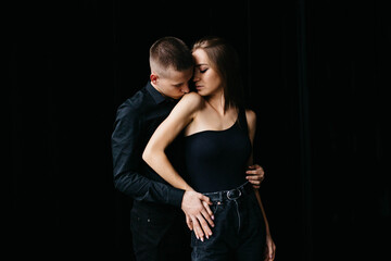 Man and woman kissing each other on a black background. The girl bites the guy on the nose. Black background Guy and girl holding hands. Couple hugging. Love.