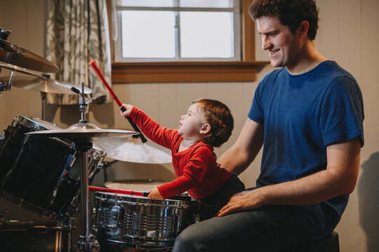 Father teaching baby boy to play drums, Parent with toddler child having fun and spending time together, Dad and kid playing music, Family hobby activity, leisure time, Fathers Day,