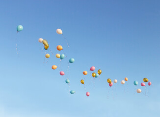 Colorful balloons soar into the blue sky