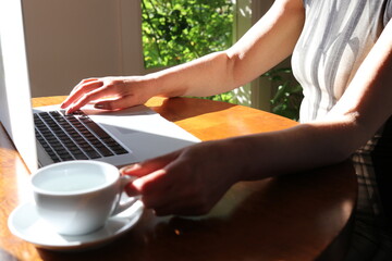 Woman working at home with laptop and a hot water drink