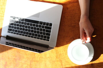 Woman working at home with laptop and a hot water drink