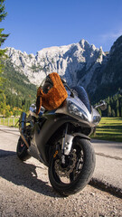 Silver sport motorcycle on the road with mountains in snow in the background in spring
