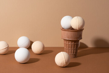 The ice-cream waffle cones with organic bath bombs for body on beige background. SPA concept.