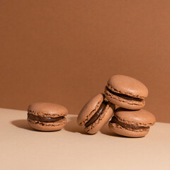 Tasty sweet brown macaroons with chocolate filling on beige background. Homemade delicious.