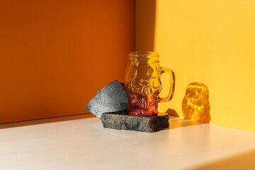 Glass mug skull on an orange background. Sunlight from the window.