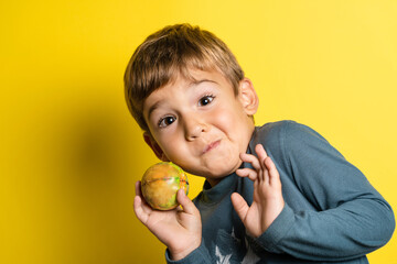 Portrait of happy joyful small caucasian boy in front of yellow background making faces - Childhood growing up and achievement concept - front view waist up copy space