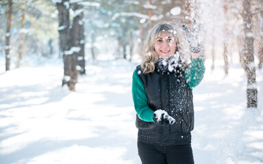 Woman plays snowballs in winter forest. Camping and tourism concept. Model surrounded by snowflakes.