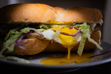 primer plano de sandwich de pan frances con huevo frito cebolla morada lechuga y. carne a la plancha 