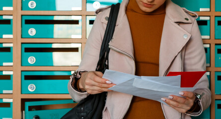 Woman attentively reading mail leaning on mailboxes