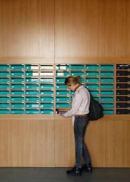 Young woman opening mailboxes and getting out letters in post