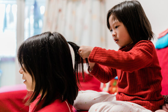 Little girl helping her mother with pigtails