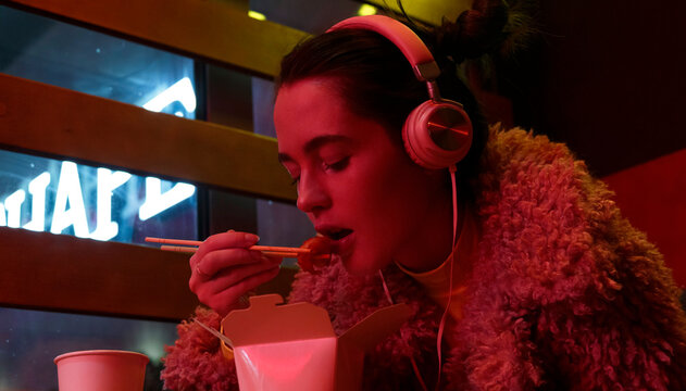 Stylish woman during dinner in neon light