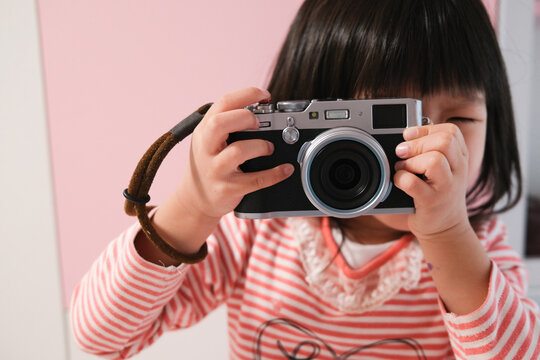 Asian little girl taking pictures with camera
