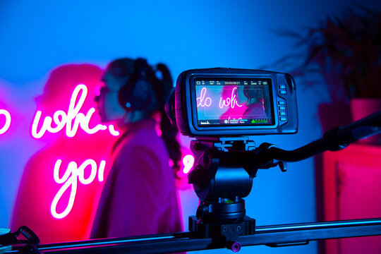 Camera shooting model against neon sign