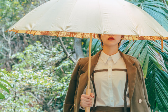 Asian young fashion woman holding umbrella in forest