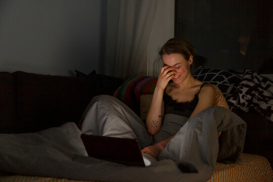 Young woman using laptop and laughing at night