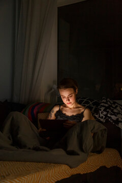 Young woman browsing tablet before sleep