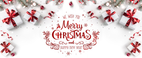 Merry Christmas text on white background with gift boxes, ribbons, red decoration, fir branches,...