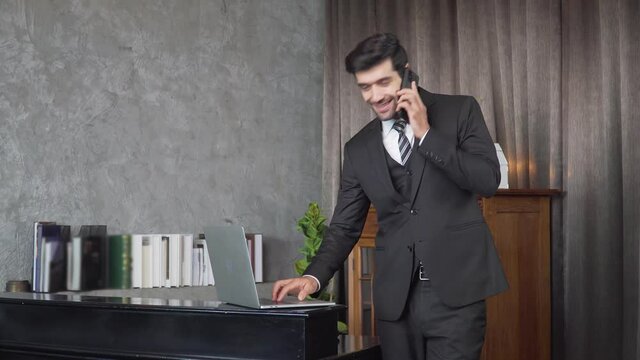 Footage B roll A Cheerful guy is working in office making mobile phone call and using laptop taking notes in notebook. Business communication. Work from home , business technology concept. 