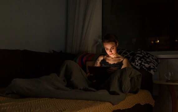 Woman browsing tablet in bed at night