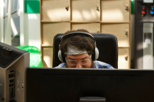 Pensive trendy man using computer with interest in modern office